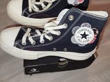 une paire de baskets Converse noires avec des lacets blancs, posée sur une boîte