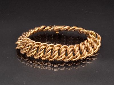 gros plan d'un bracelet en or sur une surface noire