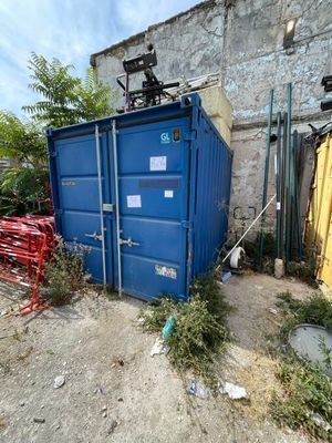 un conteneur bleu posé au milieu d'un champ de terre battue