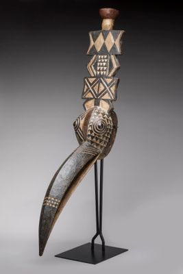 une sculpture en bois représentant un oiseau au long bec, posée sur un socle