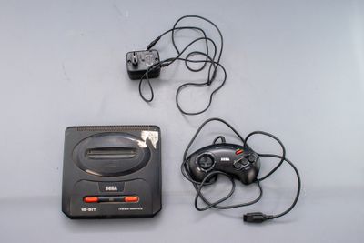 une console de jeux vidéo et une manette de jeu placées l'une à côté de l'autre