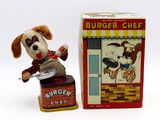 un petit chien en peluche qui se tient à côté d'une boîte de hamburgers