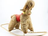 a small toy dog on a rocking horse on a white background