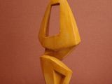 sculptures made of wood sit on a wooden base against a red wall