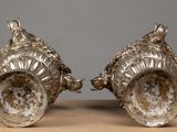 pair of silver plated vases on a table with a gray background