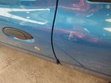 a close up of a blue car with a hole in the door