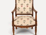 une vieille chaise en bois dont l'assise est recouverte d'un tissu à motifs floraux