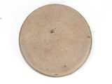 a brown plate on a white surface with a black dot