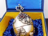 a silver egg in a blue box with a crown on top