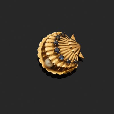 un gros plan d'une broche en or ornée de perles sur fond noir