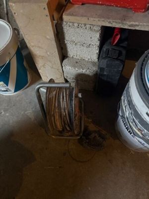 une photo représentant un seau de peinture et un tuyau d'arrosage dans un garage