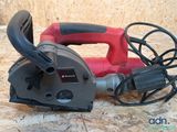a red and black electric tool on a wooden surface