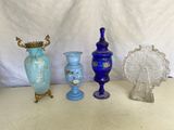Plusieurs vases en verre sont alignés sur une table devant un fond blanc.