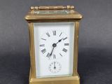 une petite horloge en or dont le cadran est orné de chiffres romains