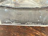 a clear glass vase with a silver lid on a wooden table