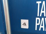 une pancarte apposée sur le côté d'une benne à ordures bleue sur laquelle on peut lire « versement d'argent - impôts »