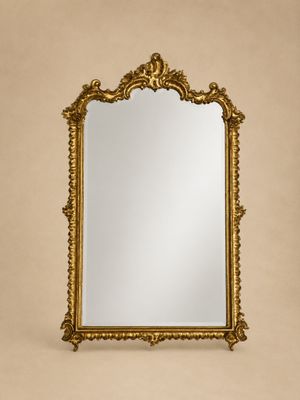 un miroir à cadre doré accroché à un mur beige dans une pièce