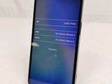 the back of a black phone with a blue screen on a white surface
