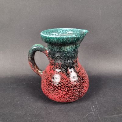a red and green vase on a black table