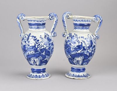 une paire de vases bleus et blancs avec des anses sur fond gris