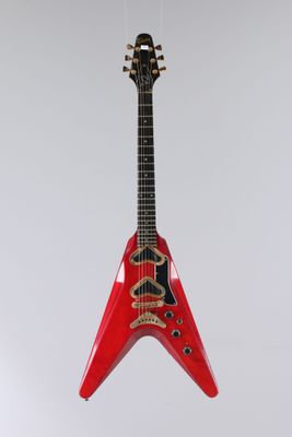 une guitare rouge suspendue à une ficelle sur un mur blanc