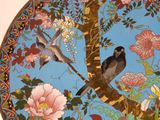 two birds perched on a tree branch in a decorative plate