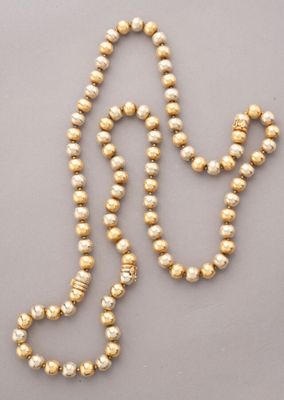 a gold beaded necklace with pearls on a gray background