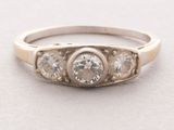 a close up of a three stone diamond ring on a white surface