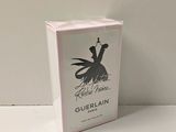 emballage d'un flacon de parfum Guerlain dans une boîte blanche posée sur une surface blanche