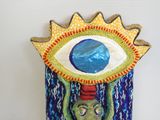 a sculpture of an eye on a wall hanging on the wall