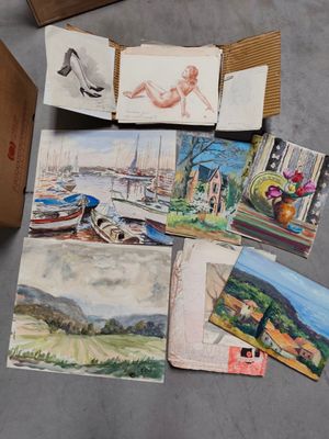 une boîte remplie de tableaux variés, posée par terre