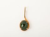 a close up of a green stone on a gold plated hook