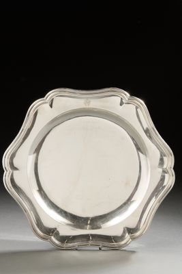 une assiette en argent aux bords festonnés sur un fond blanc