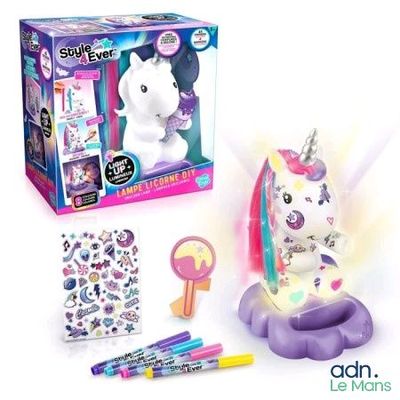 une licorne en peluche posée sur une table, à côté d'une boîte d'autocollants