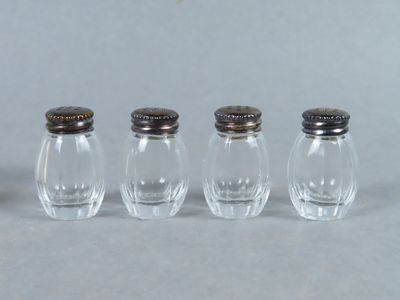 quatre petites salières et poivrières en verre alignées en rang