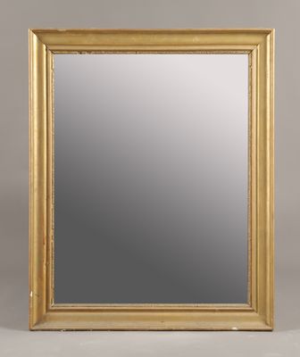 un miroir à cadre doré posé sur une surface blanche, avec un fond gris