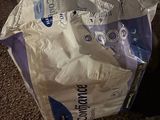 a bag of toilet paper sitting on the floor next to a suitcase