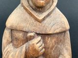 wooden figurine of a monk holding a book in his hands