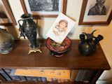 trois vases posés sur une étagère, avec des tableaux accrochés au mur derrière eux