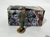 figurine représentant un homme en uniforme militaire, tenant une canne, devant une boîte