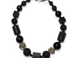 un gros plan d'un collier composé de perles noires sur fond blanc