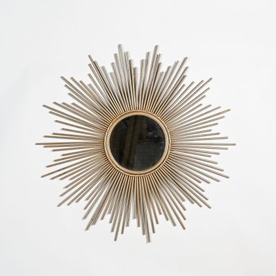 un gros plan d'un miroir en forme de rayons de soleil accroché à un mur blanc
