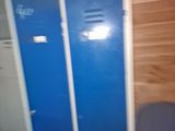 two blue lockers next to a trash can in a room