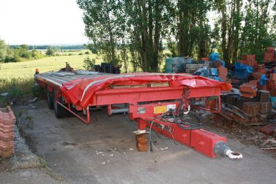 a red trailer that is parked next to a pile of bricks