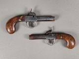 deux pistolets à crosse en bois posés sur une surface blanche