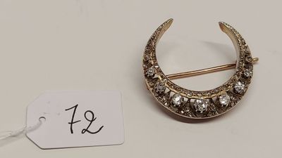 une photo d'une broche en forme de croissant en or, sertie de diamants