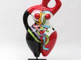 ceramic figurine of a woman holding a red vase on a black base