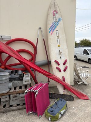 une planche de surf appuyée contre un mur, à côté d'une pile de bagages