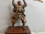 statue en bronze représentant un homme tenant une épée, posée sur un socle en bois