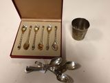 five spoons and a cup in a box on a table
